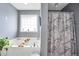 Bright bathroom showcasing a soaking tub, a patterned shower curtain, and a window providing natural light at 70 Lake Charles Xing, Covington, GA 30016