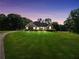 Charming brick home boasts lush lawn, mature trees, and picturesque views at dusk at 70 Lake Charles Xing, Covington, GA 30016