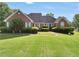 Traditional brick home featuring manicured landscaping, pristine lawn, and lakeside property at 70 Lake Charles Xing, Covington, GA 30016
