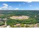 Wide aerial view of the area including buildings, a high school with a sports field, and vast green tree coverage at 164 Stoneforest Dr, Woodstock, GA 30189