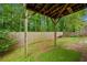 View of backyard featuring covered patio, lawn, and wood fence surrounded by lush green trees at 164 Stoneforest Dr, Woodstock, GA 30189