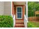 Charming brick home entrance with well-maintained landscaping, white railing and blue front door at 164 Stoneforest Dr, Woodstock, GA 30189