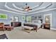 Large Primary bedroom with stylish tray ceilings, neutral carpet, and a comfortable sitting area, bathed in natural light at 2325 Manor Creek Ct, Cumming, GA 30041