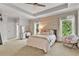 Spacious primary bedroom featuring a wood accent wall, a ceiling fan, large windows, and a cozy sitting area at 2325 Manor Creek Ct, Cumming, GA 30041