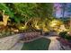 Beautiful backyard with stone walls, colorful flowers, a stone fireplace, lush greenery and a curved brick paver walkway at 3102 Royal Troon, Woodstock, GA 30189
