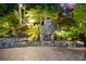 A stone fireplace sits on a brick paver patio and is surrounded by lush landscaping at 3102 Royal Troon, Woodstock, GA 30189
