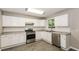 Bright kitchen with white cabinets, stainless steel appliances, and wood-look flooring at 8857 Ashwood Dr, Riverdale, GA 30274