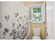 Bright bathroom features a floral shower curtain, a toilet, and a window with white shutters at 132 Eagles Club Dr, Stockbridge, GA 30281