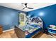 Bright blue bedroom features wood floor, ceiling fan, window, and fun decor at 5006 Dekalb Way, Stone Mountain, GA 30087