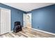 This bedroom features blue walls, wood floors, a closet, and a doorway at 5006 Dekalb Way, Stone Mountain, GA 30087