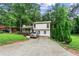 Two-story home with a long driveway and ample parking surrounded by lush green trees and grass at 5006 Dekalb Way, Stone Mountain, GA 30087