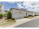 View of the white siding of the home, with a two-car garage and adjacent green space at 1023 Harvest Park Ln, Suwanee, GA 30024
