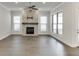 Bright living room with hardwood floors, a stone fireplace with a wooden mantle, and a ceiling fan at 1023 Harvest Park Ln, Suwanee, GA 30024