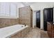 A bathroom features a large white tub with tile surround, large window and tile floors throughout at 2765 Prado Ln, Marietta, GA 30066