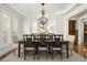 Formal dining room with modern chandelier, tray ceiling, wainscoting, and large windows at 11240 Avery Cove Ct, Alpharetta, GA 30022