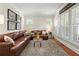 Bright living room with a brown leather sectional couch and area rug at 11240 Avery Cove Ct, Alpharetta, GA 30022
