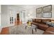 Bright living room with a brown leather sectional couch, glass coffee table, and french doors at 11240 Avery Cove Ct, Alpharetta, GA 30022