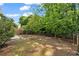 Backyard featuring an open grassy area, mature trees, wooden fence, and shade-covered ground at 3504 Benthollow Ln, Duluth, GA 30096