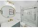Elegant bathroom with marble shower, blue vanity, gold fixtures, and a sleek, round mirror at 897 Marie Sw Ln, Conyers, GA 30094