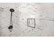 Close-up of a marble-walled shower with matte-black showerhead and soap nook at 897 Marie Sw Ln, Conyers, GA 30094