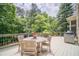Outdoor back deck surrounded by mature trees, with patio table set for outdoor dining at 5650 Buckleigh Pointe, Suwanee, GA 30024