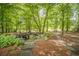 Picturesque backyard landscape featuring lush greenery, mature trees, and a stone sitting area at 5650 Buckleigh Pointe, Suwanee, GA 30024