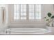 Bright bathroom with a relaxing soaking tub beneath shuttered windows, perfect for unwinding at 5650 Buckleigh Pointe, Suwanee, GA 30024
