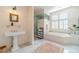 Well-lit main bathroom with pedestal sink, soaking tub, and glass-enclosed shower at 5650 Buckleigh Pointe, Suwanee, GA 30024