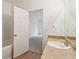 Bright bathroom with a single sink vanity featuring a light countertop, white door, and access to the bathtub at 1065 City Park Dr, Mcdonough, GA 30252