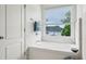 Bright bathroom featuring a soaking tub with tile surround, a window, and modern fixtures at 1229 Concord Se Rd, Smyrna, GA 30080