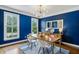 Modern dining room with blue walls, wood floors, stylish lighting, and bright windows at 1229 Concord Se Rd, Smyrna, GA 30080