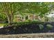 Landscaped front yard with a stone wall, mulch beds, mature trees and an archway leading to the home at 608 Sherwood Ne Rd, Atlanta, GA 30324