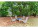 Backyard fire pit area featuring Adirondack chairs surrounded by lush trees at 4525 E Point Dr, Cumming, GA 30041