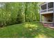 Manicured backyard with mature trees, green grass and patio seating area at 1686 Brooks Farm Nw Dr, Acworth, GA 30101