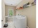 Well-lit laundry room with washer, dryer, shelving, and a window for natural light at 944 Hidden Falls Se Ln, Smyrna, GA 30082