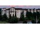 Modern apartment building with dark trim and multiple balconies surrounded by lush greenery and colorful sky at 901 Abernathy Ne Rd # 2050, Sandy Springs, GA 30328