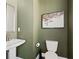 A stylish powder room featuring a modern pedestal sink, toilet, and green accent wall at 1815 La Dawn Nw Ln, Atlanta, GA 30318