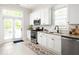 Beautiful kitchen features white cabinetry, stainless appliances, granite countertops, and french doors to the deck at 230 Milton Se Ave, Atlanta, GA 30315
