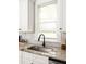 Granite countertops pair with white cabinets and modern fixtures around the kitchen sink and window at 230 Milton Se Ave, Atlanta, GA 30315
