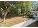 Spacious backyard with a lush green lawn, mature trees, and a screened-in porch for enjoying the outdoors at 2604 Flat Shoals Sw Rd, Conyers, GA 30094