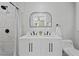 Bathroom featuring double sinks with black fixtures, white cabinets, modern mirror, and tiled shower at 2604 Flat Shoals Sw Rd, Conyers, GA 30094