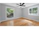 Bright bedroom featuring hardwood floors, a ceiling fan, and two windows overlooking a lush landscape at 2604 Flat Shoals Sw Rd, Conyers, GA 30094
