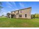 Large backyard view of a two-story home with a covered patio, big yard, and blue sky at 81 Homesite Hartsfield Rd, Mcdonough, GA 30253