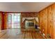 Living room with a brick fireplace, wood paneling, hardwood floors, and access to a sunroom at 3539 Evans Mill Rd, Lithonia, GA 30038
