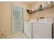 A functional laundry room with washer, dryer, and storage shelf at 502 Fortune Ridge Rd, Stone Mountain, GA 30087