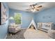 Bedroom room with blue walls, ceiling fan, decorative teepee, and crib near a window at 47 Gloster Mill Way, Lawrenceville, GA 30044