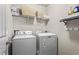 Laundry room with white washer and dryer, and overhead storage shelves at 47 Gloster Mill Way, Lawrenceville, GA 30044