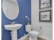 Stylish powder room featuring a pedestal sink, oval mirror, and nautical-themed artwork at 508 Regency Trl, Acworth, GA 30102