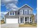 Two story home with gray siding, stone accents, a covered porch with rocking chairs, and an attached two car garage at 508 Regency Trl, Acworth, GA 30102