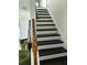 Staircase with dark laminate treads, white risers, and a wooden handrail leading to the upper level at 5458 Stagecoach Rd, Ellenwood, GA 30294